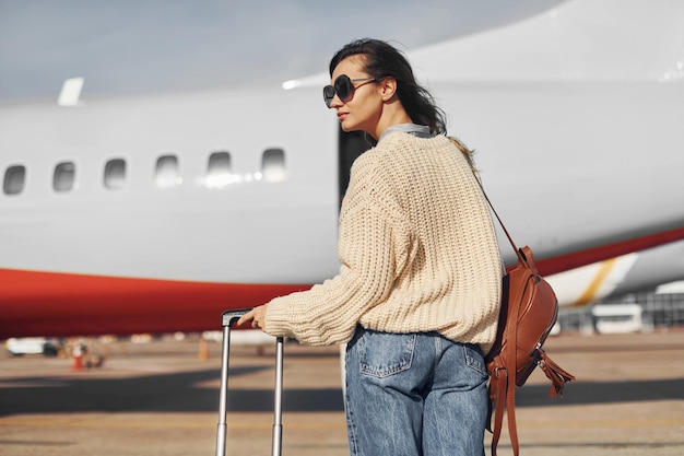 Photo pendant la journée, une jeune passagère en vêtements décontractés est à l'extérieur près de l'avion