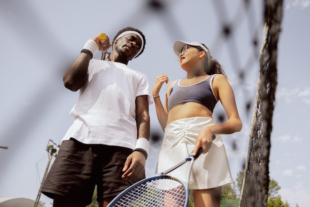 Pendant le match de tennis, un gars d'apparence africaine écoute attentivement la fille qui explique la stratégie