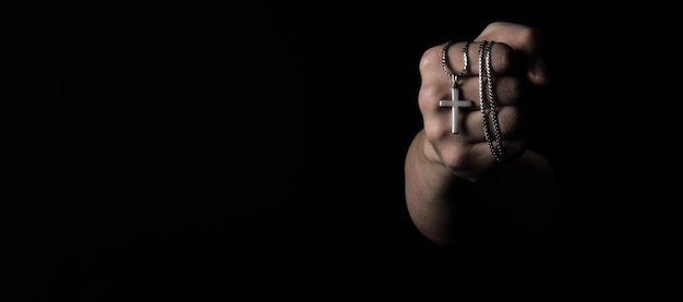 Pendentif crucifix ou signe de croix en argent et tenir dans la main de l'homme représente la prière pour quelqu'un