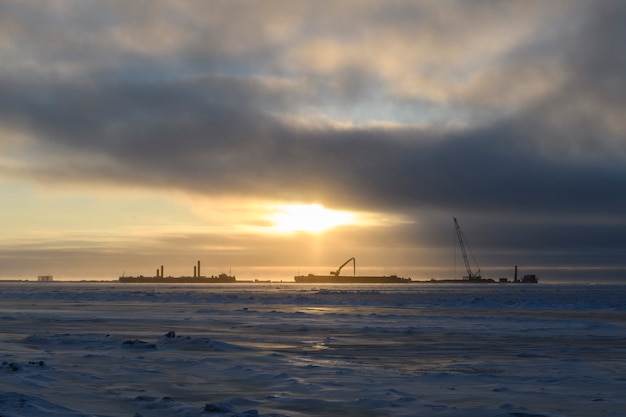 Péniche avec grue. Dragueur travaillant en mer. Coucher de soleil en mer arctique. Travaux maritimes de construction offshore.