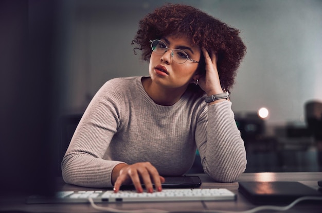 Pensée confuse et nuit avec une programmeuse noire travaillant tard dans son bureau pour la cybersécurité Idée doute et heures supplémentaires avec une développeuse au travail pour la recherche ou l'analyse de données