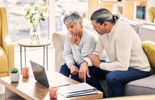 Pensée informatique et planification du couple âgé documents financiers et financement de la retraite ou prêt à domicile assurance-vie canapé et gestion des actifs de la femme âgée homme et stress de la dette sur l'ordinateur portable