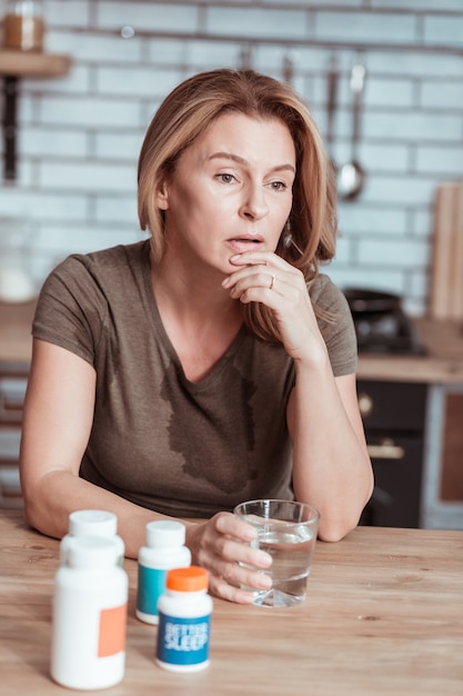 Pensées suicidaires. Femme stressée aux cheveux blonds ayant des pensées suicidaires en regardant la médecine