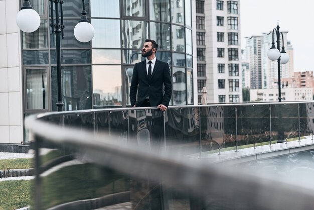 Penser aux affaires. Beau jeune homme en costume complet à l'écart tout en se tenant à l'extérieur