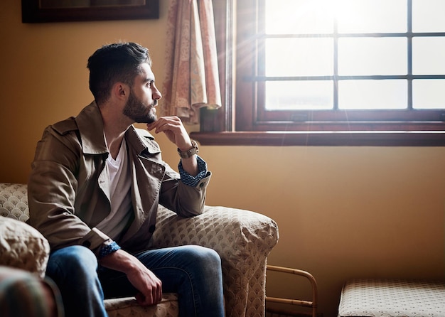 Penser les choses à travers Photo d'un beau jeune homme plongé dans ses pensées alors qu'il était assis sur une chaise à la maison