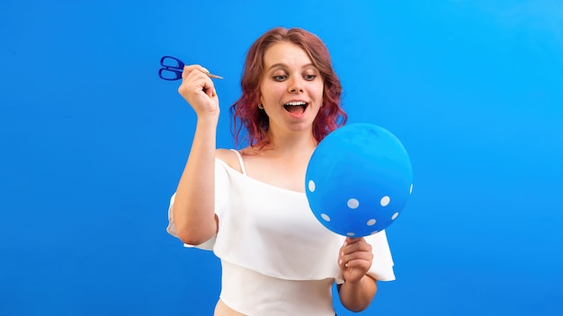 Penser surpris femme caucasienne avec un ballon et des ciseaux