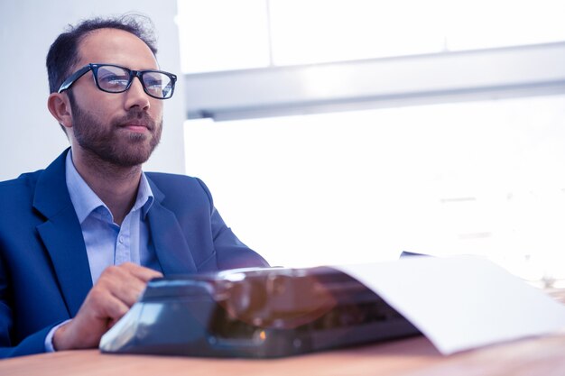 Pensif, homme affaires, regarder loin, pendant, travailler, sur, machine à écrire, à, bureau, dans, créatif, bureau