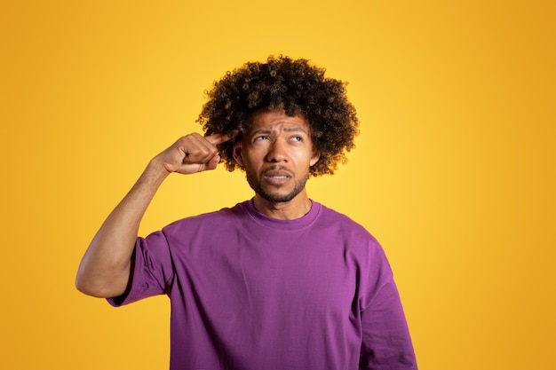 Pensif triste confiant adulte afro-américain bouclé homme en t-shirt violet met son doigt au temple