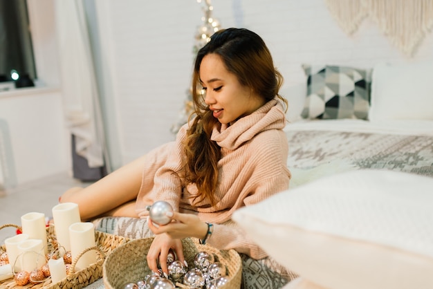 Pensive jeune jolie femme asiatique avec des bougies allumées la veille de Noël faisant un vœu