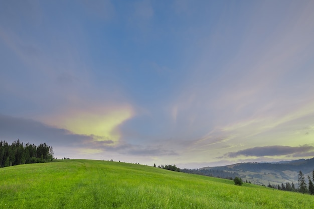 Pente de la montagne avec de l'herbe verte contre le ciel à l'aube