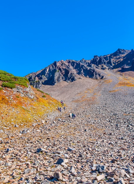 Pente en pierre du volcan avec des touristes à pied.