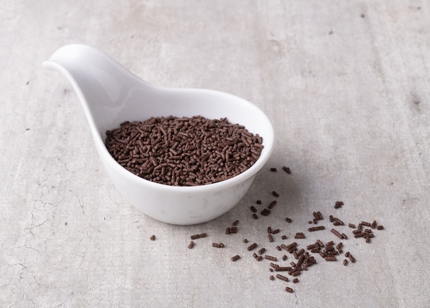 Des pépites de chocolat noir dans un bol blanc. Garniture de brigadeiro brésilienne typique.