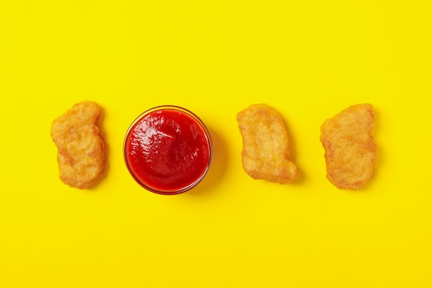 Pépites de poulet frit et ketchup sur fond jaune