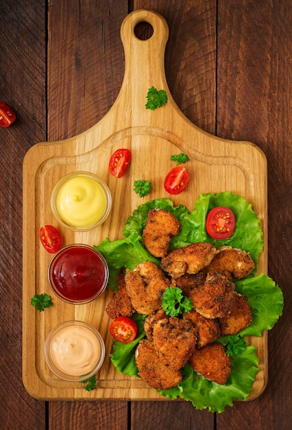 Pépites de poulet et sauce sur une table en bois