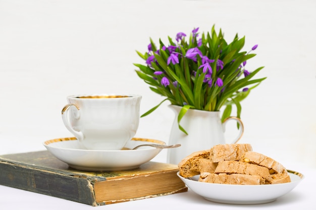 Perce-neige dans un vase, une tasse de thé et biscotti sur la table