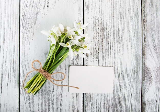 Perce-neige fleurs avec carte sur une table en bois