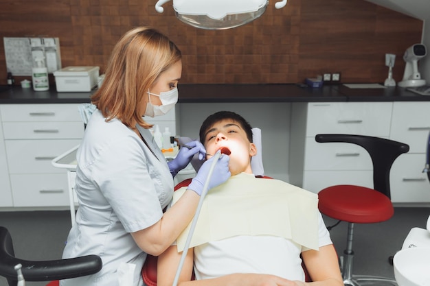 Percer les dents et aspirer la salive avec un dentiste éjecteur traite les dents du patient dans un cabinet dentaire moderne