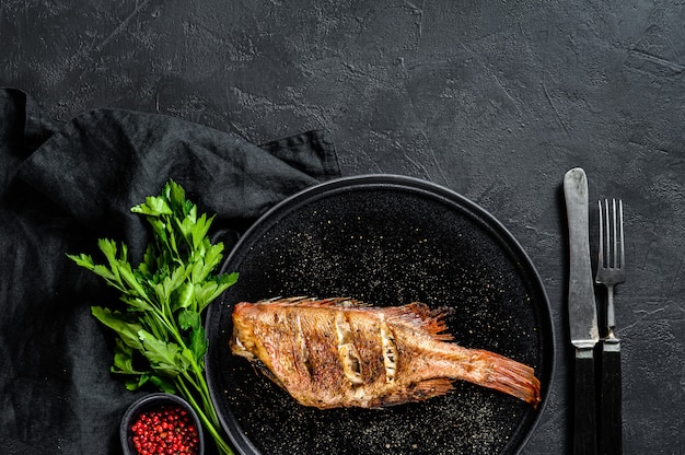 Perche de mer frite servie sur une assiette ronde au persil.