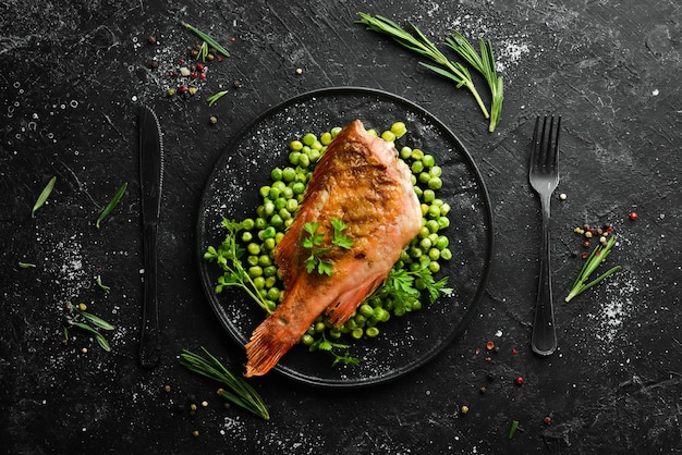 Perche rouge de mer cuite au four avec des pois verts sur une plaque de pierre noire Vue de dessus Espace de copie gratuit