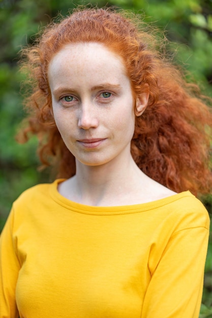 Perdre le portrait d'une fille aux cheveux roux avec des taches de rousseur regardant la caméra