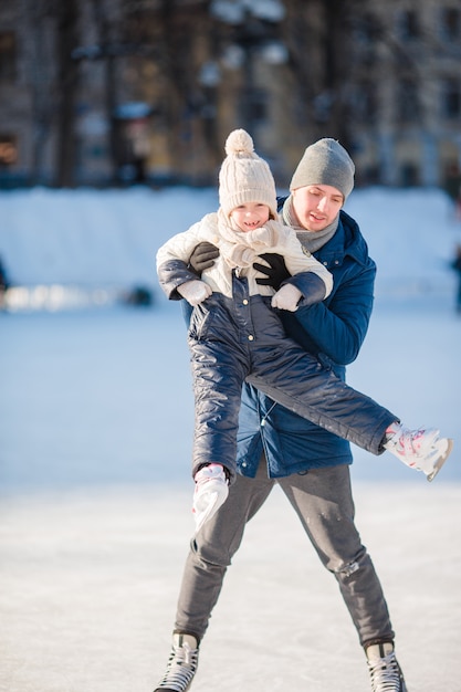 Père et adorable petite fille s'amusant sur la patinoire en plein air