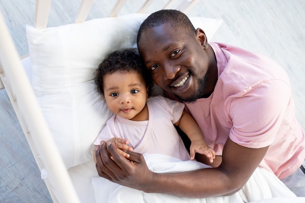 Un père afro-américain embrasse son bébé dans son berceau avant de se coucher