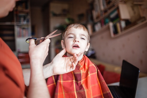 Père d'âge moyen coupant les cheveux de son petit fils seul à la maison