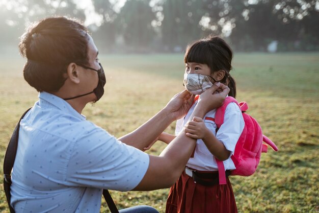 Père aidant sa fille à porter un masque avant d'aller à l'école