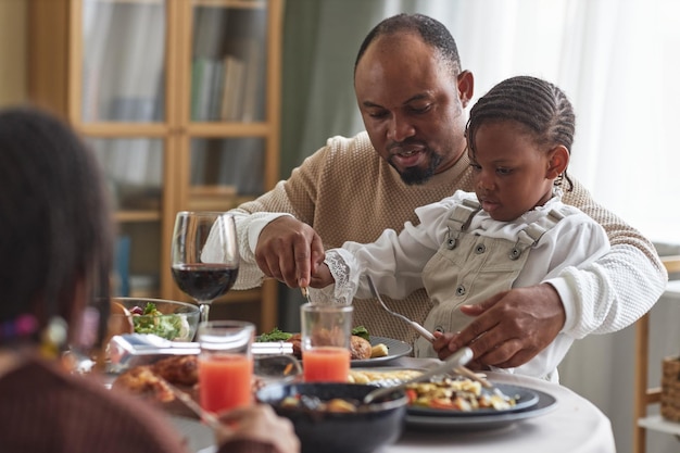 Père aidant son enfant à manger un repas