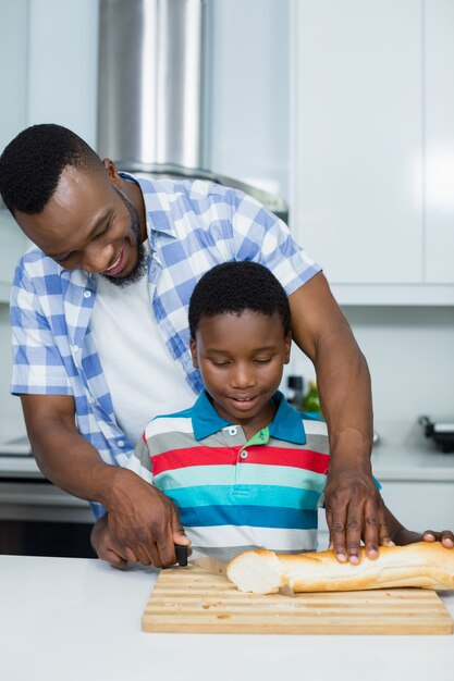 Père aidant son fils à couper le pain dans la cuisine