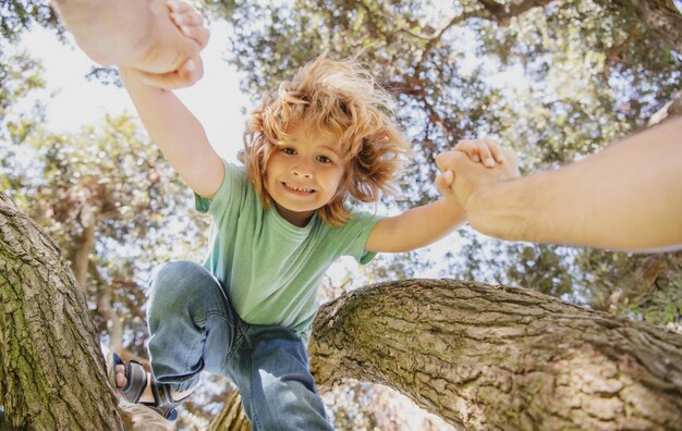 Père aidant son fils à grimper à l'arbre pères main protection de l'enfant mode de vie sain pour les parents