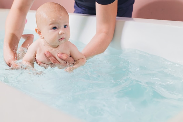 Un père aide son petit garçon pendant les cours de natation dans la piscine.