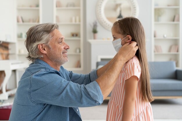 Père ajustant le masque protecteur à sa fille de 6 ans avant de sortir pendant la pandémie de Covid-19.