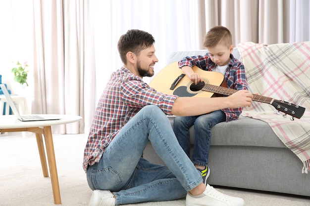 Père apprenant à son fils à jouer de la guitare à la maison