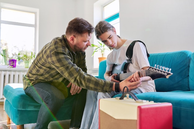 Père apprend à son fils adolescent à jouer de la guitare électrique