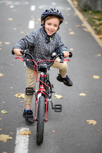 Le père apprend à son fils à faire du vélo sur la piste cyclable du parc Le père tient un vélo et le fils est assis dessus