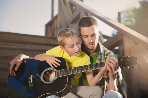 Photo père apprend à son fils à jouer de la guitare