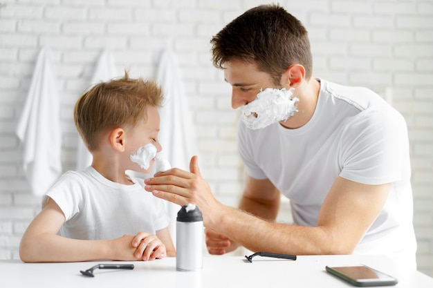 Le père apprend à son petit-fils à se raser le visage dans la salle de bain