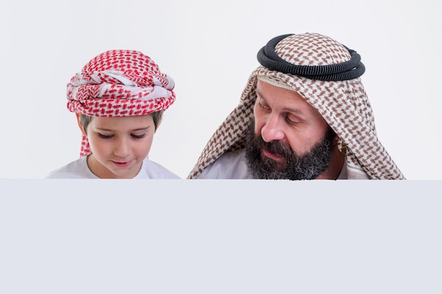 Père arabe avec son fils tenant une affiche blanche et tirant la langue stock photo