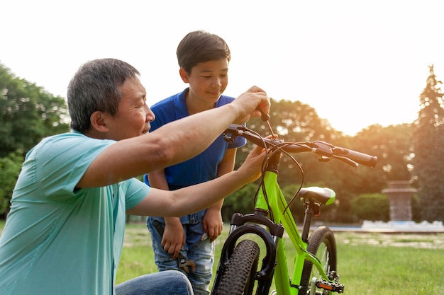 Un père asiatique aide son fils à réparer son vélo avec des outils. Un petit garçon coréen regarde son père réparer un vélo cassé.