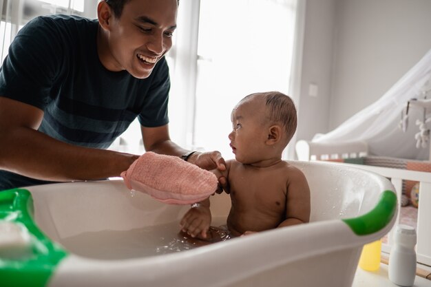 Père asiatique donnant un bain à son bébé