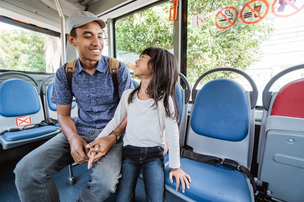 Père asiatique emmenant sa fille à l'école en empruntant les transports publics en bus