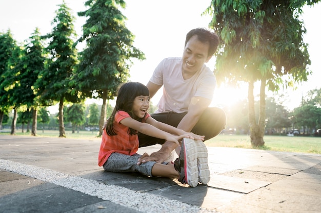 Le père asiatique et la petite fille font des exercices en plein air
