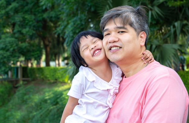 Un père asiatique porte une jolie fille sur sa poitrine.