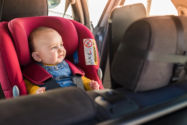 Le père attache son petit bébé au siège d'auto.