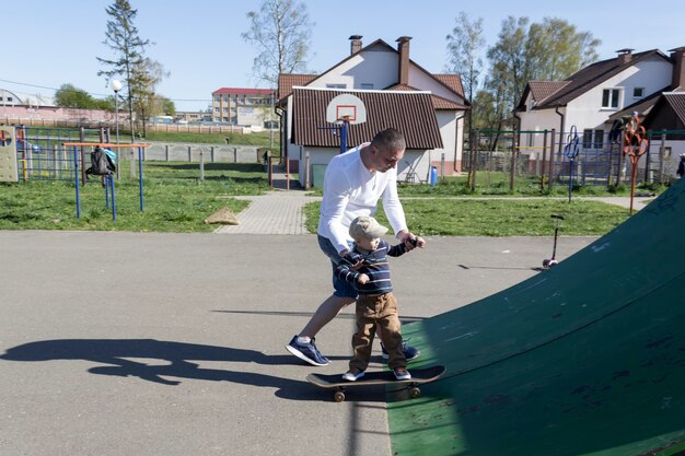 Un père attentionné et aimant apprend à son fils de trois ans à faire du skateboard