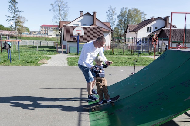 Un père attentionné et aimant apprend à son fils de trois ans à faire du skateboard