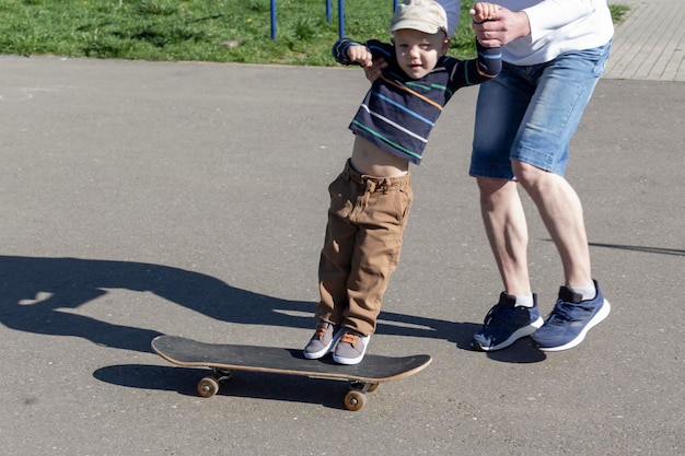 Un père attentionné et aimant apprend à son fils de trois ans à faire du skateboard