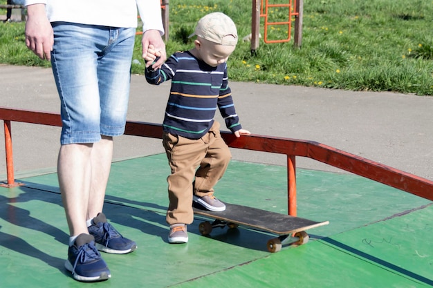 Un père attentionné et aimant apprend à son fils de trois ans à faire du skateboard