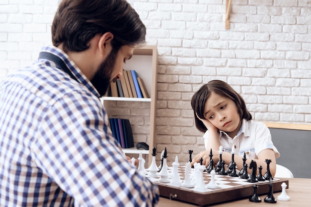 Un Père Barbu Adulte Joue Aux échecs Avec Son Fils Adolescent à La Maison.